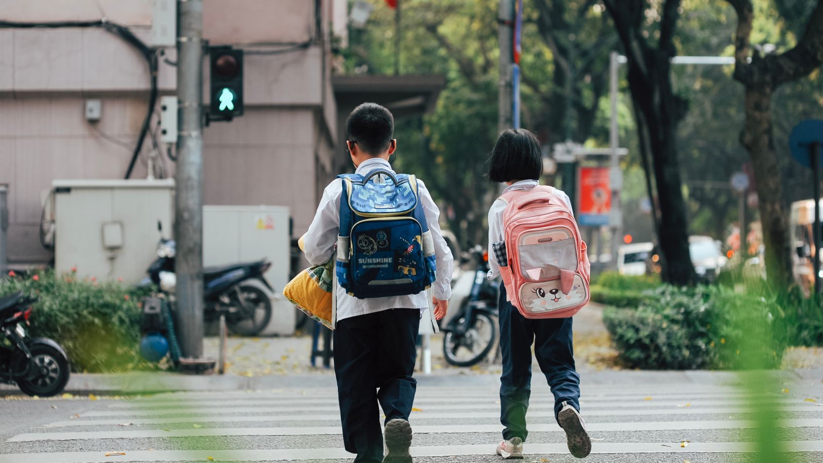 Photograph of two learners in school uniforms with backpacks walking to school