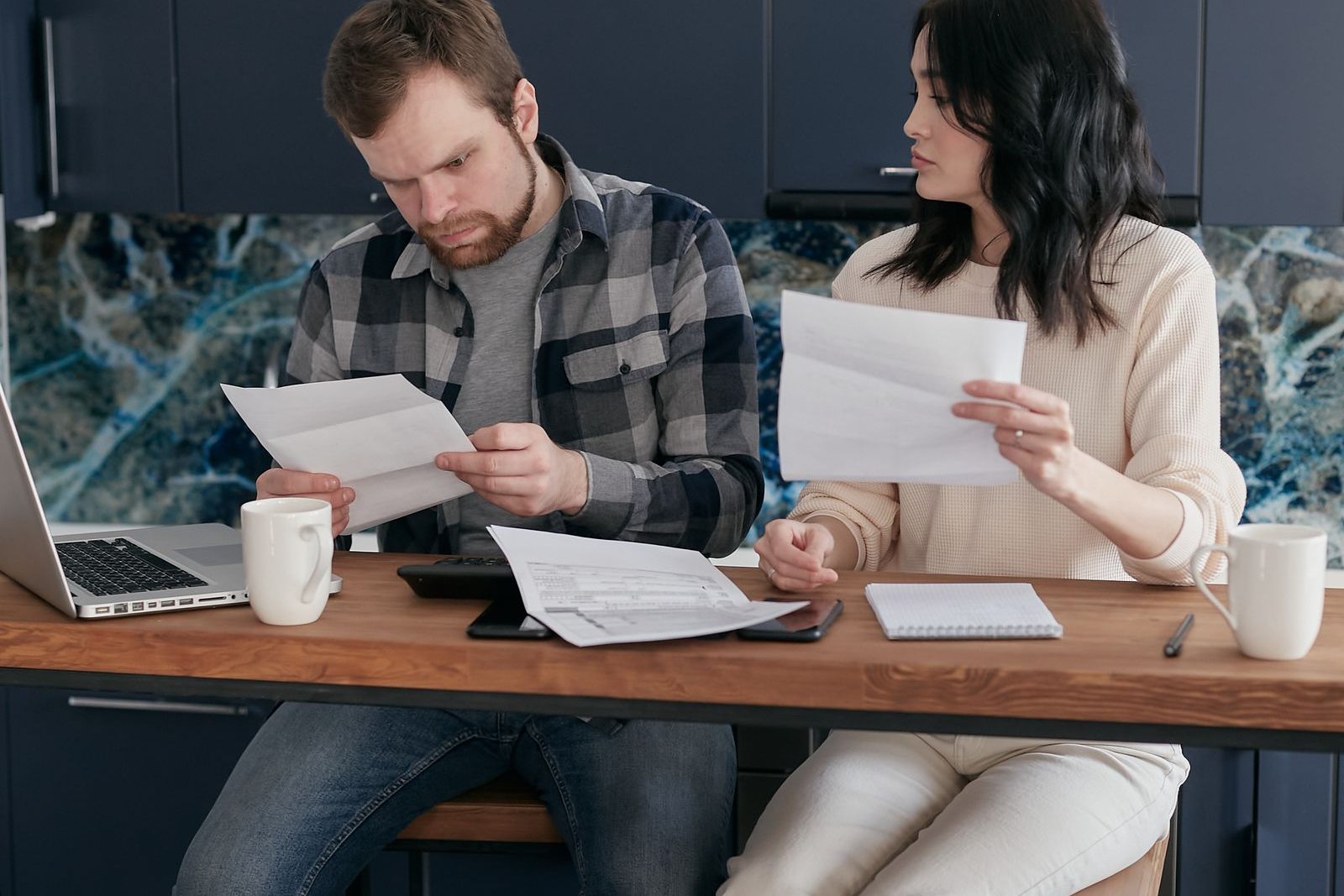 Photograph of a parent at home surrounded by bills and receipts for school fees