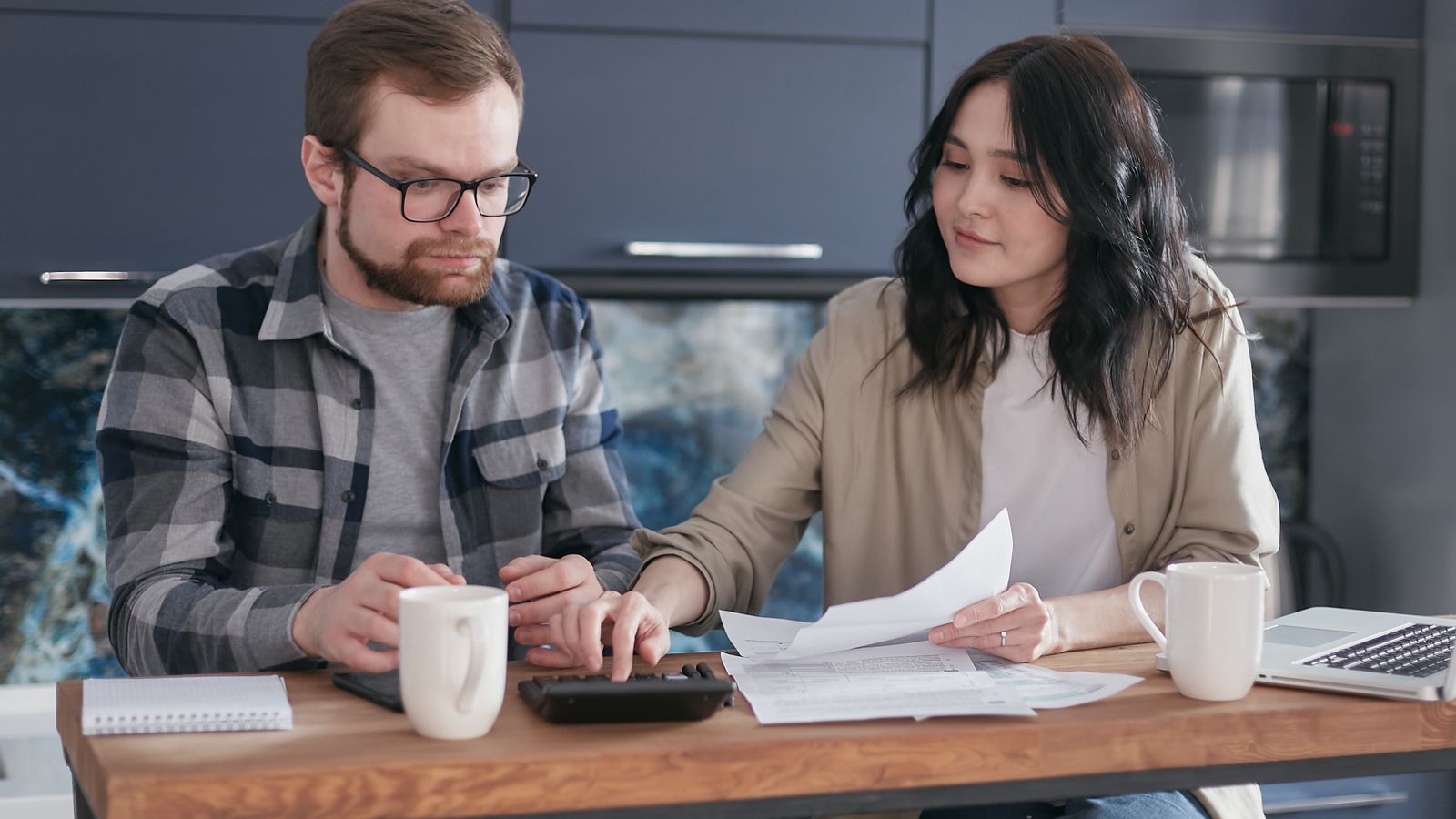 Photograph of a parent reviewing a school fee statement and household documents at home