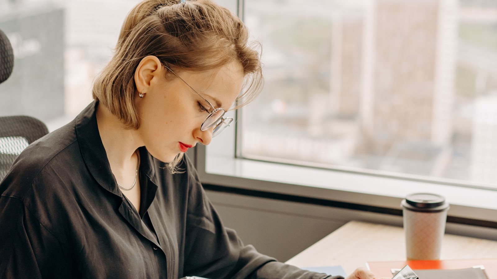 Photograph of a bursar reviewing financial documents at her desk during month-end
