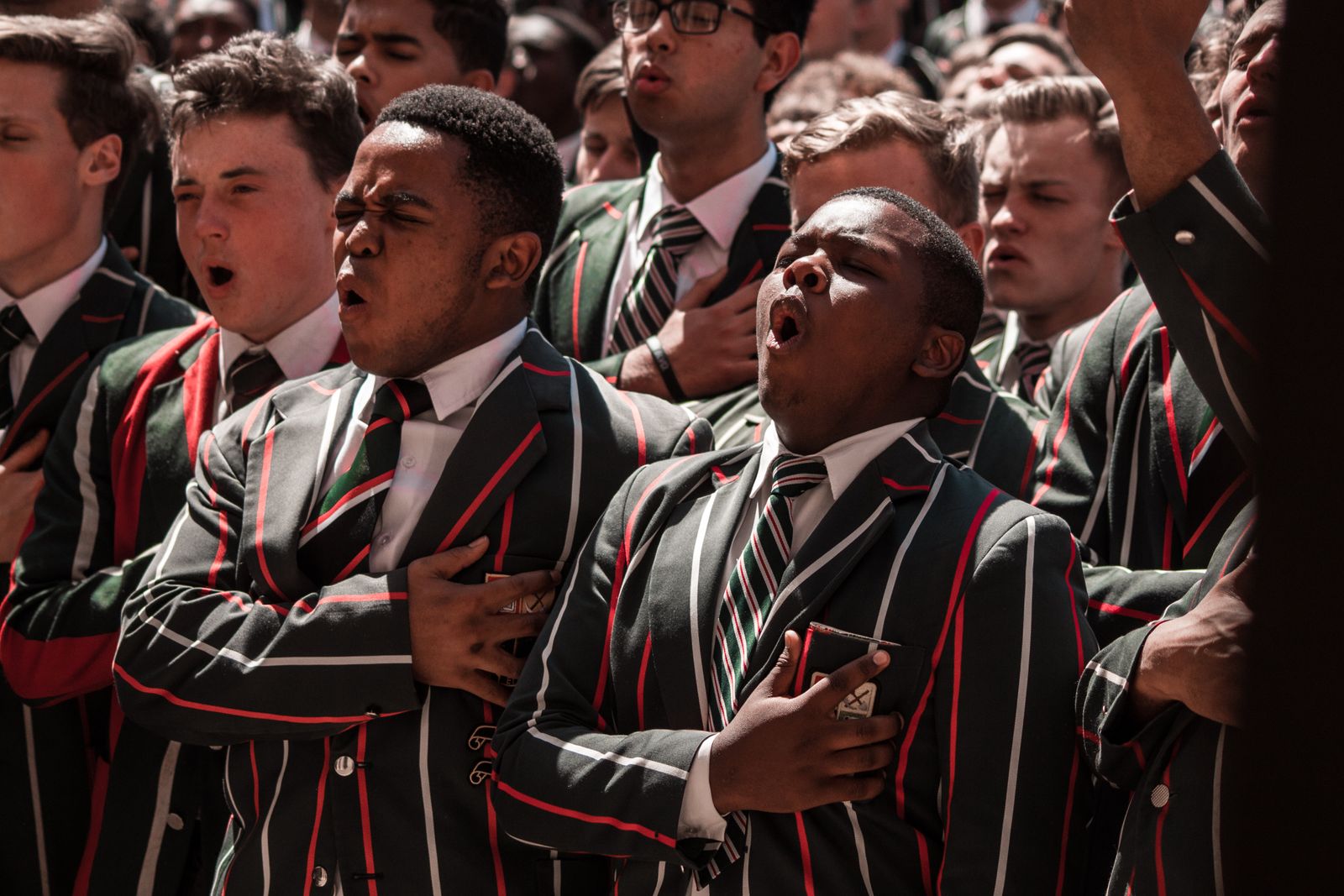 Photograph of students in uniform singing at a school assembly